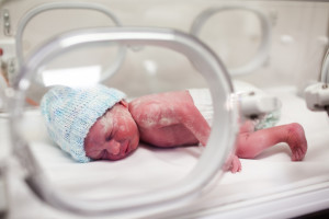 Newborn baby boy covered in vertix in incubator